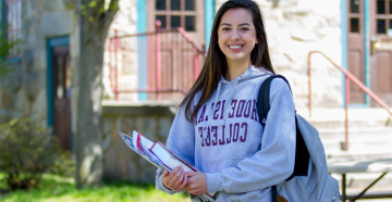 Student in RIC sweatshirt outside Roberts Hall 